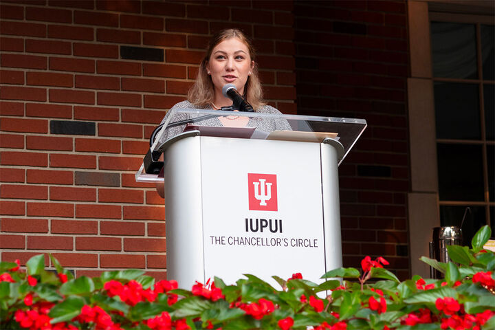 A student speaks at a podium during an IUPUI chancellor's event.